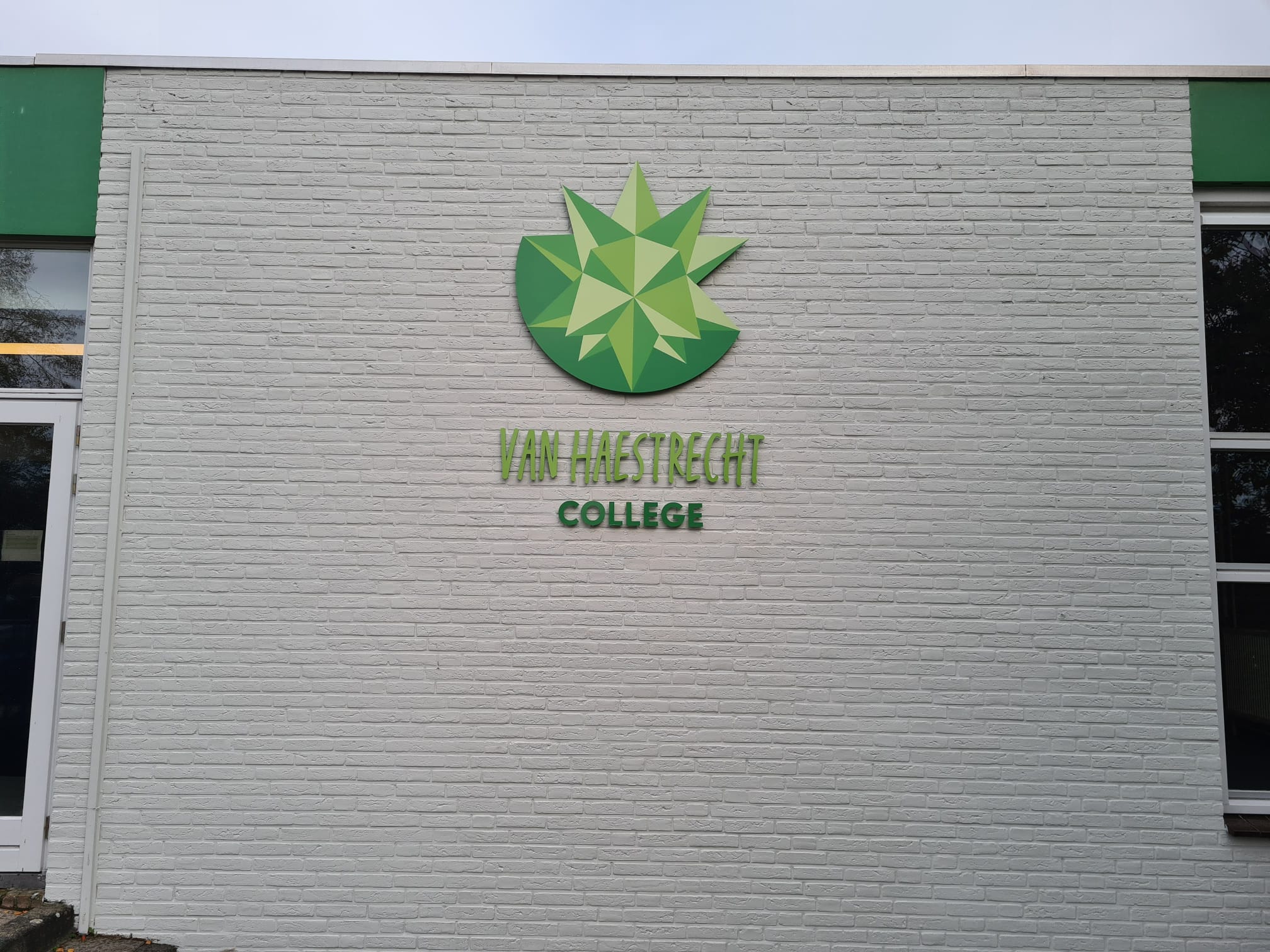 detail logo gefreesd op gevel Van Haestrecht College